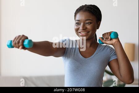 Nahaufnahme Portrait Of Sporty Black Female Macht Übungen Mit Hanteln Zu Hause Stockfoto