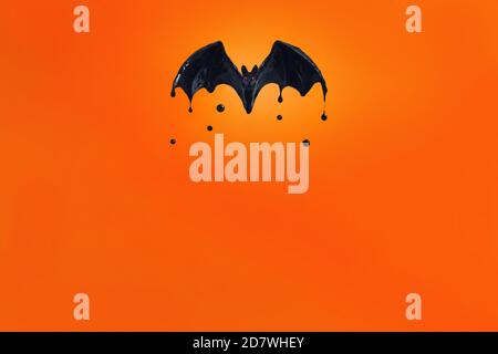 Schwarze Fledermaus mit roten Augen auf orangefarbenem Hintergrund. Stockfoto