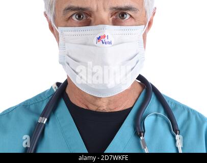 Nahaufnahme eines Arztes mit einem Sticker, den ich gewählt habe, auf der COVID-19 Schutzmaske, die er zur Abstimmung trug. Der Mann trägt chirurgische Peelings mit einem Stethoskop. Stockfoto