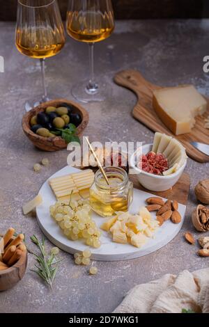 Verschiedene Käsesorten auf Marmorplatte mit Feigen, Nüssen, Trauben und Honig Stockfoto