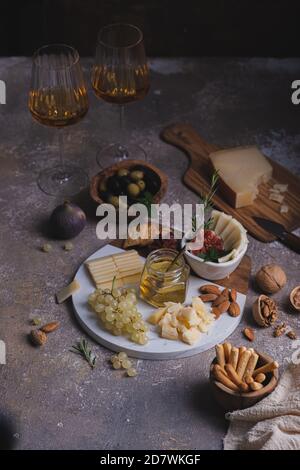 Verschiedene Käsesorten auf Marmorplatte mit Feigen, Nüssen, Trauben und Honig Stockfoto
