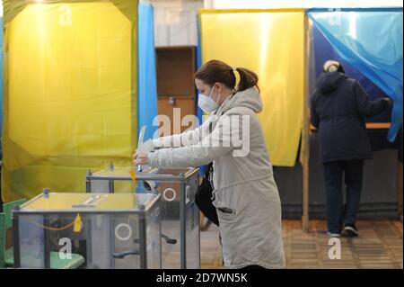 Eine Wählerin, die eine Facemask als vorbeugende Maßnahme gegen das Covid-19-Coronavirus trug, sah, wie sie ihre Stimme während der Kommunalwahlen an eine Wahlurne in einem Wahllokal warf.Wähler in der ganzen Ukraine gehen zu ihren lokalen Wahllokalen, um ihre Stimme abzugeben, um ihre Bürgermeister am lokalen Wahltag 2020 zu wählen. Stockfoto