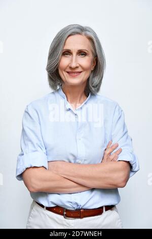 Selbstbewusst lächelnde reife Frau auf grauem Hintergrund, vertikales Porträt. Stockfoto