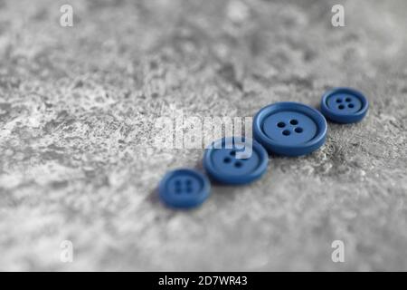 Stapel von blauen matten Tasten auf Beton Hintergrund, Makro Bokeh. Schöne Nadelarbeit. Zum Nähen verwenden. Leerzeichen für Text Stockfoto