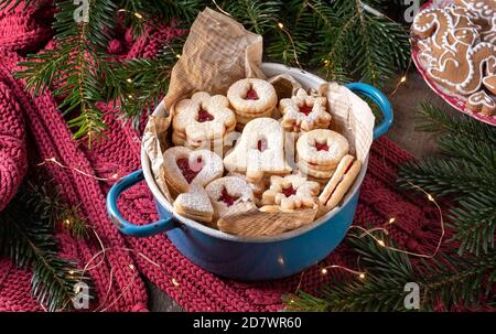 Linzer Weihnachtsplätzchen gefüllt mit Marmelade, mit Tannenzweigen und Lebkuchen im Hintergrund Stockfoto