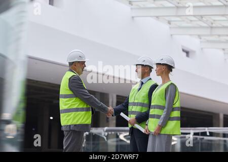 Seitenansicht Porträt lächelnder Geschäftsleute, die nach einem Investitionsvertrag auf der Baustelle die Hände schütteln, Platz kopieren Stockfoto
