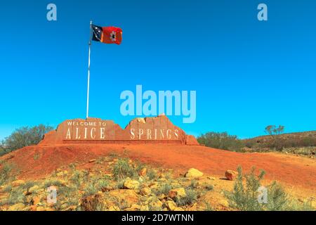 Alice Springs Willkommensschild und australische Flagge des Northern Territory in Zentralaustralien. Tourismus im Outback Red Centre Wüste. Blauer Himmel mit Kopie Stockfoto