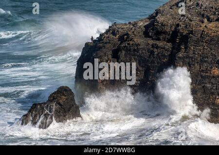 Zwei Fischer trotzen riesigen Wellen auf Klippen in der Nähe von Perranporth Cornwall als starke Winde schlagen den Südwesten der Vereinigtes Königreich Stockfoto