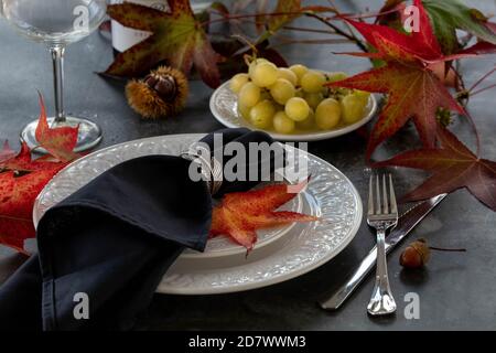 Tisch im Herbststil mit roten Blättern, Trauben und einer Flasche Wein. Selektiver Fokus. Stockfoto