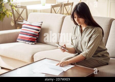 Indische Frau hält Telefon mit mobilen E-Bank-Anwendung Rechnungen bezahlen in App. Stockfoto