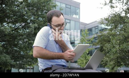 Business man mit Tablet und Laptop während der Gespräche auf dem Smartphone Stockfoto