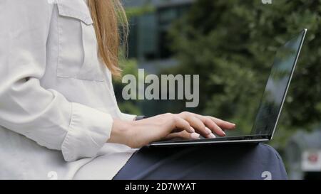 Frau, die im Freien an einem Laptop arbeitet. Stockfoto