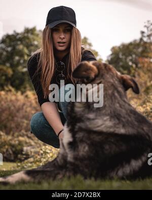 Vertikale Aufnahme einer Frau, die einen schockierten Ausdruck macht, als sie versucht, den Stock aus dem Mund des Hundes zu ziehen. Spielen Sie ein Spiel von fetch und der Hund gewann Stockfoto