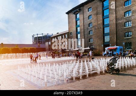 King's Cross London, Großbritannien, 12. Juli 2019: Kornspeicher-Platz Menschen genießen draußen, Brunnen Stockfoto