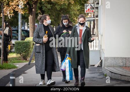 BELGRAD, SERBIEN - 17. OKTOBER 2020: Frauen, junge Mädchen, Spaziergang mit Lebensmitteln, einschließlich Essen, Toilettenpapier und Wein tragen Gesichtsmaske Atmung p Stockfoto