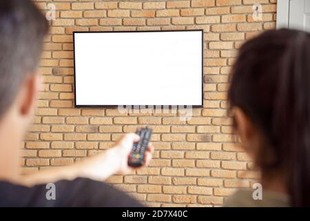 Paar halten Fernbedienung Fernsehen Mockup weißen Bildschirm zu Hause. Stockfoto