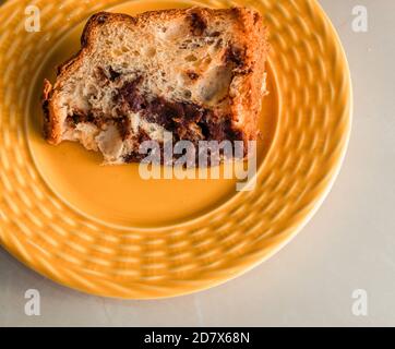 Traditionelle Weihnachts-Panettone (Chocottone) auf gelbem Teller. Köstliche Panettone-Scheibe, traditionelles italienisches Dessert zu Weihnachten. Nahaufnahme Stockfoto