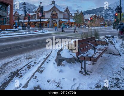 Abendansicht einer Straßenbank, Fußgänger und Geschäfte auf der Banff Avenue in Banff, Alberta, Kanada Stockfoto