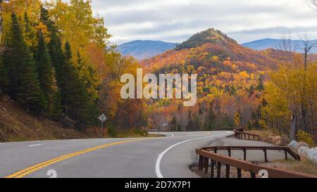 Kurvenreiche Straße durch Herbstbäume mit Herbstfarben in Adirondacks, New York, New England Stockfoto