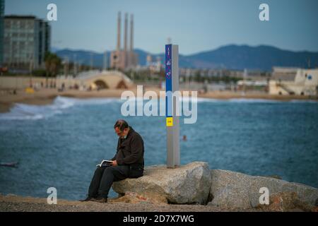 Madrid, Spanien. Oktober 2020. Ein Mann liest am 25. Oktober 2020 ein Buch am Bogatell-Strand in Barcelona, Spanien. Der spanische Ministerpräsident Pedro Sanchez hat am Sonntag den Alarmzustand angekündigt, um die Ausbreitung des Coronavirus zu stoppen, wenige Tage nachdem Spanien der erste Staat der Europäischen Union war, der die düstere 1-Millionen-Marke überschritten hat. Quelle: Joan Gosa/Xinhua/Alamy Live News Stockfoto