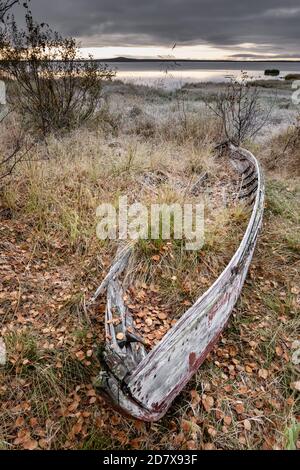 Dramatische Landschaft mit kleinen verlassenen Holzboot an der Seeufer in Finnland. Stockfoto