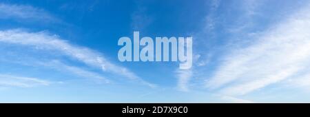 Durchscheinende Zirruswolkenstreifen schweben an einem sonnigen Tag langsam hoch in einem strahlend blauen Himmel. Panoramaaufnahme der Skyline. Wetter und Meteorologie. Stockfoto