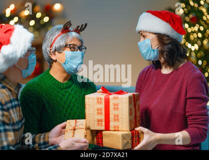 Menschen mit Geschenken tragen Gesichtsmasken während Coronavirus und Grippe Ausbruch an Weihnachten. Schutz vor Viren und Krankheiten, Quarantäne zu Hause. COVID-2019 Stockfoto