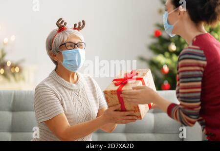 Menschen mit Geschenken tragen Gesichtsmasken während Coronavirus und Grippe Ausbruch an Weihnachten. Schutz vor Viren und Krankheiten, Quarantäne zu Hause. COVID-2019 Stockfoto