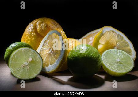 Stillleben, Grüne und gelbe Zitronen auf einem rustikalen Holztisch, Scheiben und ganze Zitronen in a b fehlen Hintergrund Zitrusfrüchte Konzepte Stockfoto