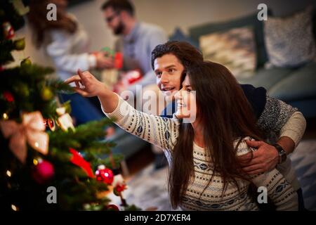 Erwachsene Paare haben Spaß über Weihnachtsbaum Stockfoto