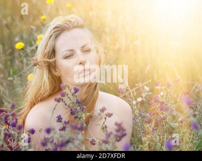 Künstlerische Porträt der Sommersprossen Frau auf natürlichen Hintergrund. Junge Frau genießt die Natur zwischen den Blumen und Gras. Nahaufnahme Sommerportrait Stockfoto