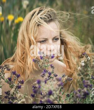 Künstlerische Porträt der Sommersprossen Frau auf natürlichen Hintergrund. Junge Frau genießt die Natur zwischen den Blumen und Gras. Nahaufnahme Sommerportrait Stockfoto