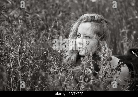 Schwarz-Weiß-künstlerische Porträt der Sommersprossen Frau auf natürlichem Hintergrund. Junge Frau genießt die Natur zwischen den Blumen und Gras. Nahaufnahme Sommer po Stockfoto