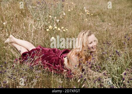 Künstlerische Porträt der Sommersprossen Frau auf natürlichen Hintergrund. Junge Frau genießt die Natur zwischen den Blumen und Gras. Nahaufnahme Sommerportrait Stockfoto