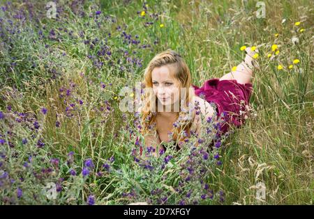 Künstlerische Porträt der Sommersprossen Frau auf natürlichen Hintergrund. Junge Frau genießt die Natur zwischen den Blumen und Gras. Nahaufnahme Sommerportrait Stockfoto