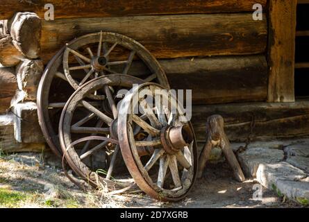 Holzräder von einem alten Wagen vor stehen Die Wand eines hölzernen Landhauses Stockfoto