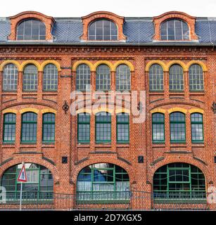 Rote Ziegelfassade eines alten Industriegebäudes mit großem Glas fenster Stockfoto