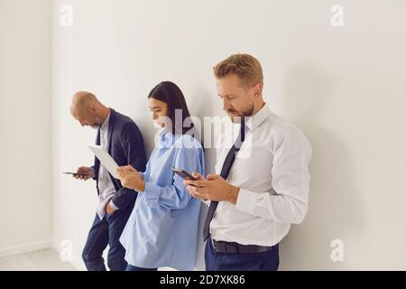 Seriöse Büroangestellte unterschiedlichen Alters mit modernen Gadgets während Pause bei der Arbeit Stockfoto