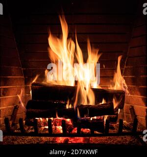 Brennender Kamin. Gemütliches warmes Zuhause, weihnachtszeit. Holzstämme Feuer glühen im Dunkeln. Nahaufnahme Stockfoto