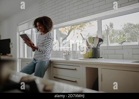 Junge afrikanische Frau in der modernen Küche mit digitalen Tablet stehen Stockfoto