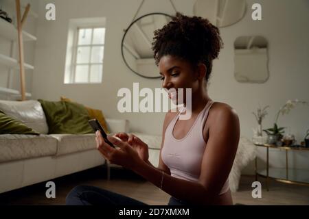 Glückliche junge Frau, die Yoga macht und das Handy benutzt Auf dem Boden Stockfoto