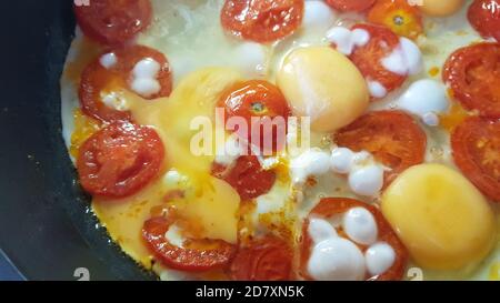 Rühreier mit runden Scheiben Tomaten werden in einer Pfanne gekocht, Nahaufnahme Stockfoto