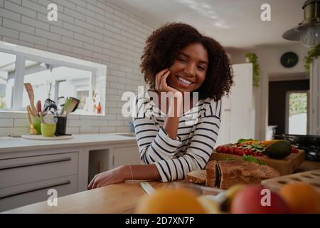 Junge Frau, die sich mit gehacktem Gemüse auf der modernen Küchentheke stützt Und Brot Stockfoto