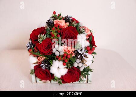 Bouquet mit roten Rosen, Baumwollkugeln, Zapfen, Fichte und anderen Blumen. Kreis Blumen Haufen und Buch auf Tisch, Draufsicht Stockfoto