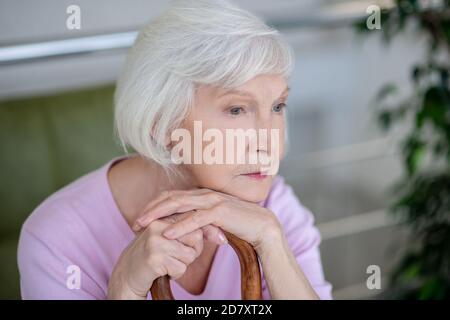 Grauhaarige Frau in rosa Hemd suchen ernst und nachdenklich Stockfoto