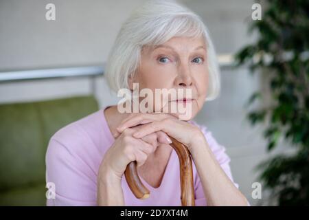 Grauhaarige Womanwith Walking Stick suchen ernst und nachdenklich Stockfoto