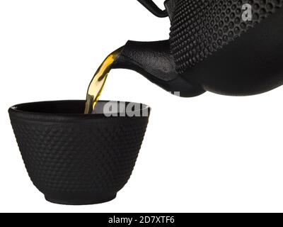 Tee Gießen auf schwarze Tasse isoliert. Teezeremonie. Strom von Tee aus einem Wasserkocher Stockfoto