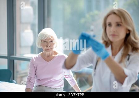Weibliche junge Krankenschwester hält eine Ampulle mit Impfstoff und suchen Konzentriert Stockfoto