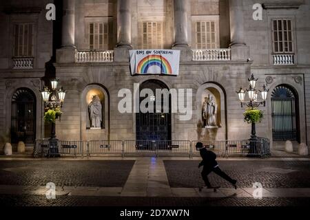 Barcelona, Spanien. Oktober 2020. 25. Oktober 2020, Barcelona, Katalonien, Spanien: In der ersten Nacht der Ausgangssperre kommt ein Skater an Barcelonas Hauptfassade des Rathauses vorbei. Der spanische Premierminister hat heute einen neuen Ausnahmezustand genehmigt, der bis Mai in Kraft bleiben soll, und die katalanische Regierung verhängt zwischen 22 und 6 Uhr eine obligatorische Ausgangssperre. Quelle: Jordi Boixareu/Alamy Live News Stockfoto