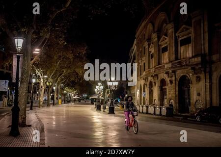 Barcelona, Spanien. Oktober 2020. 25. Oktober 2020, Barcelona, Katalonien, Spanien: Eine Frau radelt in der ersten Nacht der Ausgangssperre durch den einsamen Boulevard von Las Ramblas in Barcelona. Der spanische Premierminister hat heute einen neuen Ausnahmezustand genehmigt, der bis Mai in Kraft bleiben soll, und die katalanische Regierung verhängt zwischen 22 und 6 Uhr eine obligatorische Ausgangssperre. Quelle: Jordi Boixareu/Alamy Live News Stockfoto